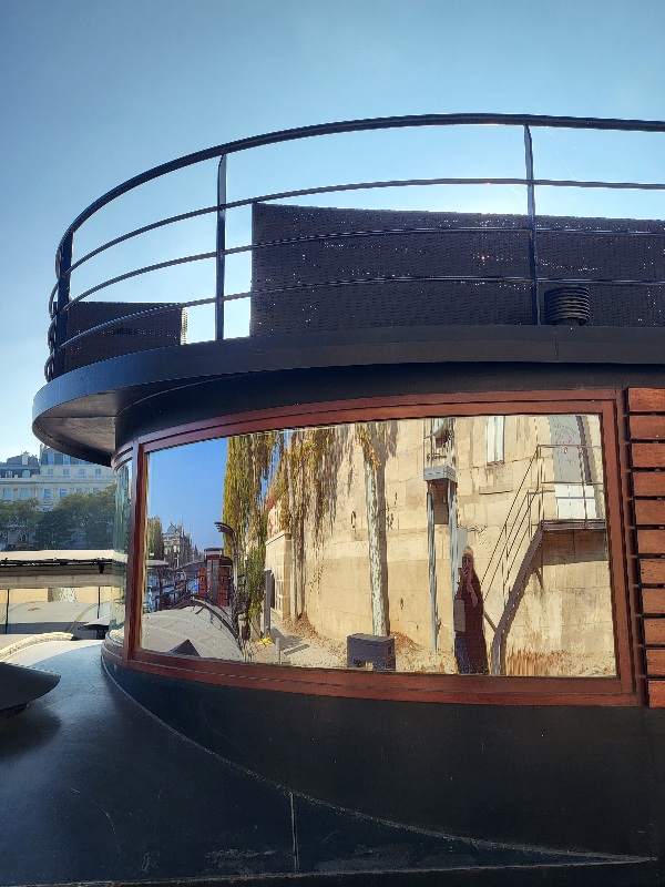 En longeant la Seine, un reflet fugace dans la fenêtre d&rsquo;une&nbsp;péniche.